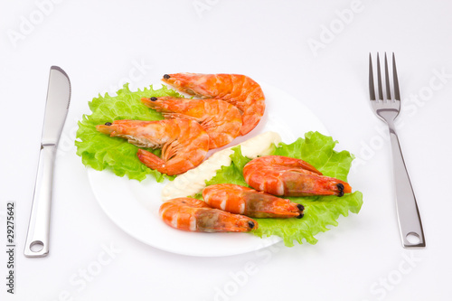 Royal shrimps on leaves of green salad in a white plate