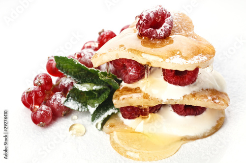 Heart shaped pancakes topped with honey, raspberries, mint and P