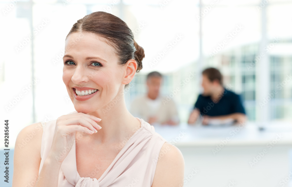 Smiling businesswoman looking at the camera while her coworkers
