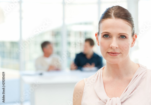 Serious businesswoman looking at the camera while her coworkers