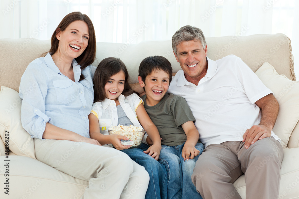 Family watching tv while they are eating popcorn Family watching tv while they are eating popcorn