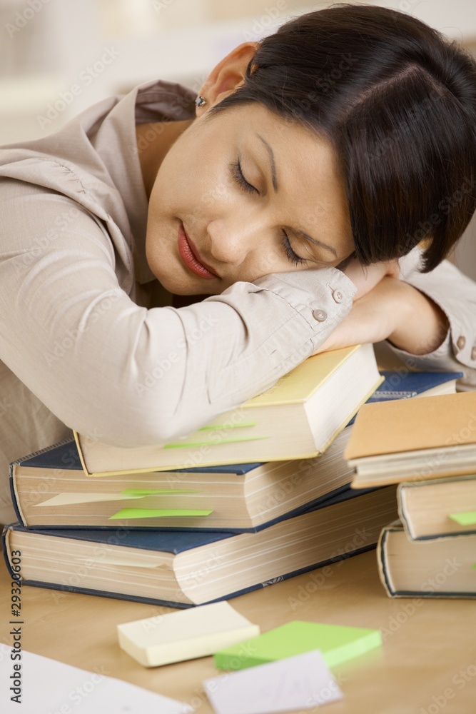 Tired college student sleeping on pile of books Tired college student sleeping on pile of books