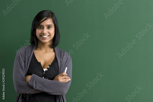 Smiling teacher crossed the arms for the blackboard