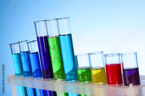 Multicoloured test tubes in the stand on blue background