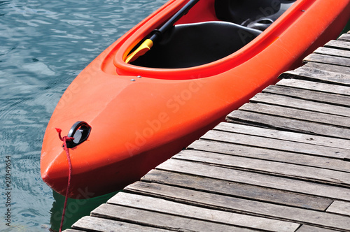 Orange kayak floating on lake beside wooden dock