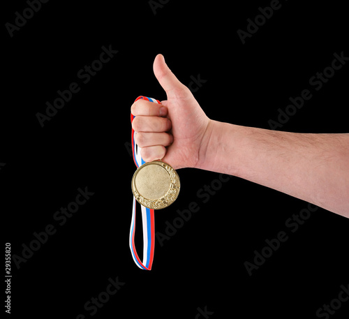Gold medal in hand isolated on black