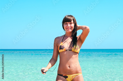 Young sexy girl standing in sea and listening to music