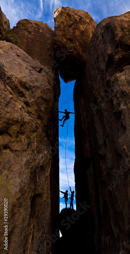 Team of climbers struggel up a steep cliff. photo