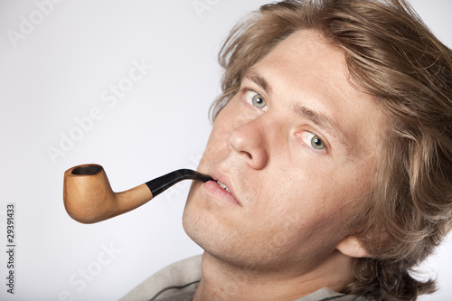 Attractive young man smoking pipe