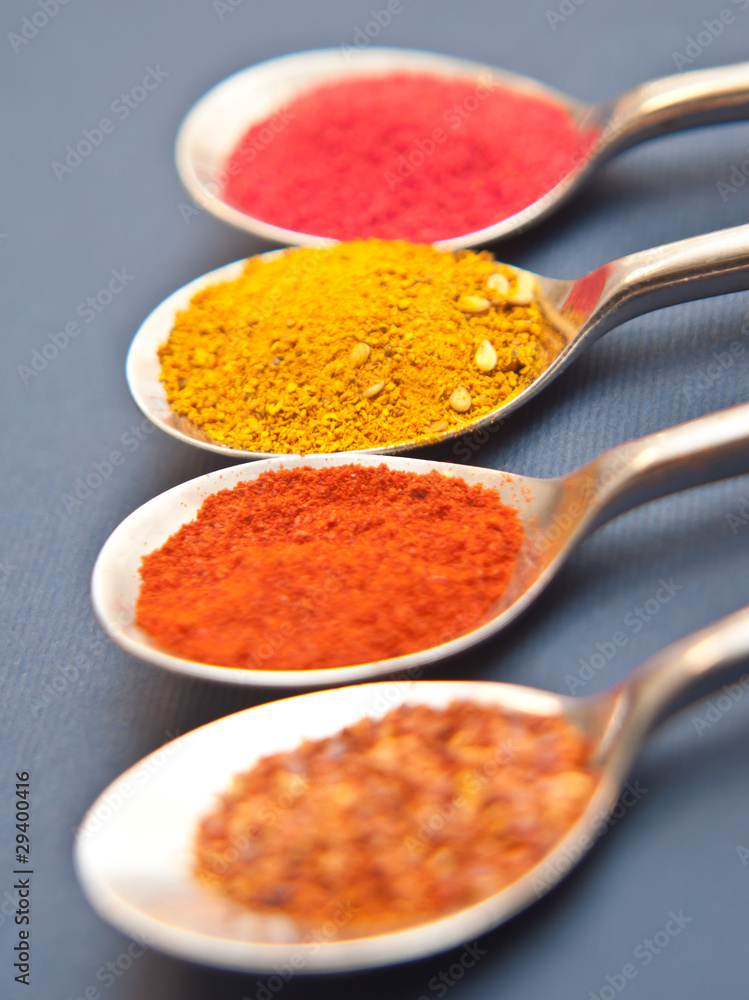 Four spices presented in teaspoons over dark blue background Four spices presented in teaspoons over dark blue background