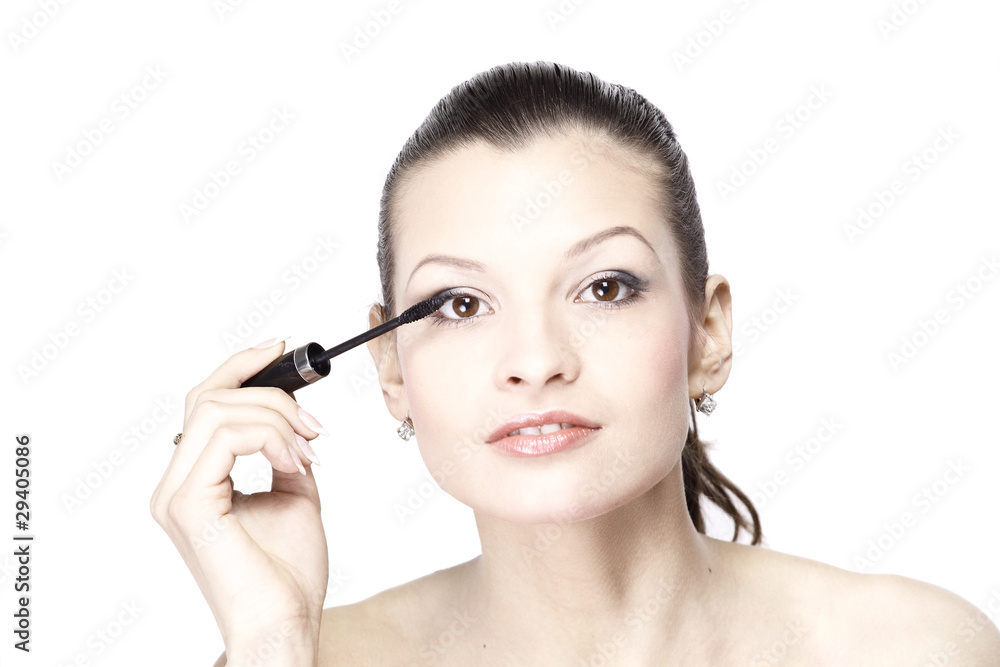 Portrait of pretty young woman applying mascara using
