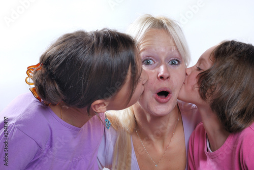 A mother smiles as she receives a kiss on the cheek from her you