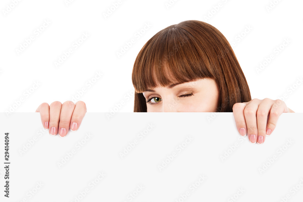 Winking woman peeking over blank billboard Winking woman peeking over blank billboard