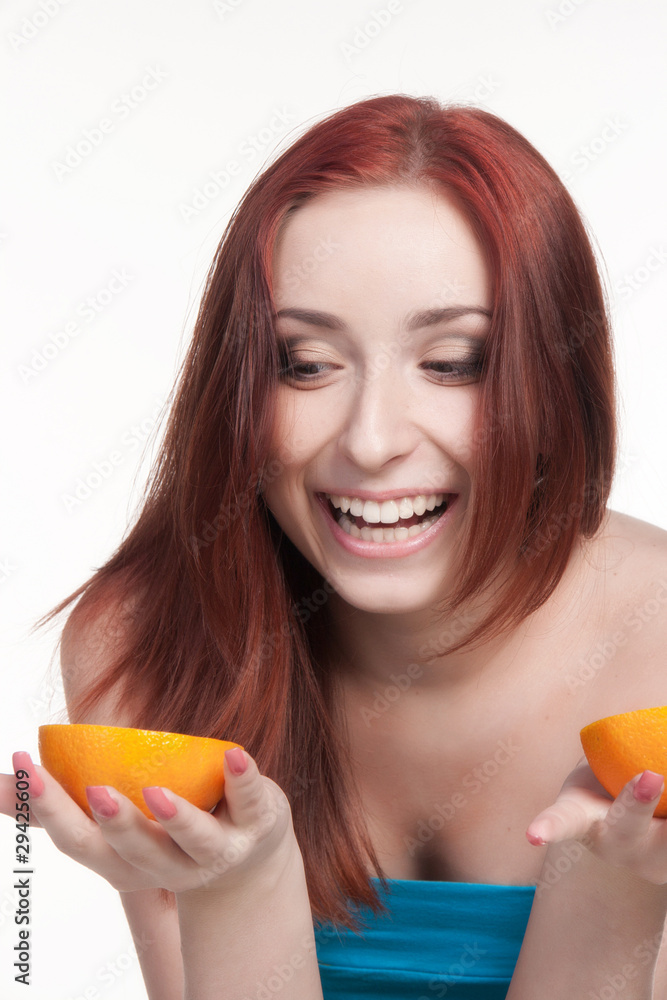 A beautiful redhead woman holding two halves of orange A beautiful redhead woman holding two halves of orange