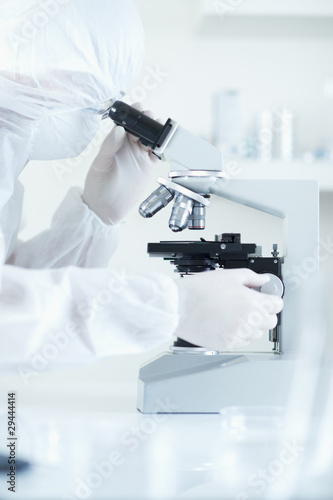 scientist in sterile environment with microscope