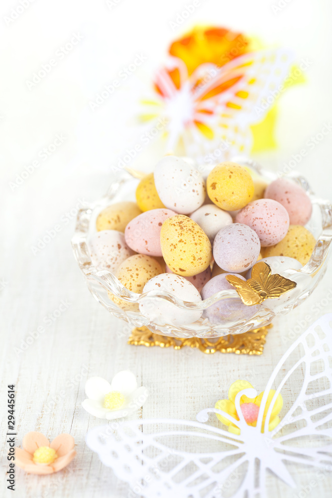 chocolate speckled eggs in bowl with paper batterfly on white ta chocolate speckled eggs in bowl with paper batterfly on white ta