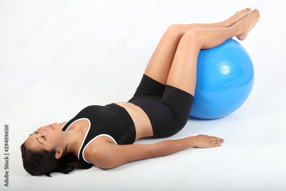 Fit young woman concentrating using exercise ball Fit young woman concentrating using exercise ball