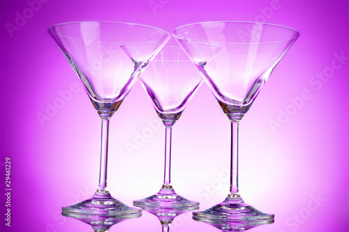 Three empty martini glasses on purple background