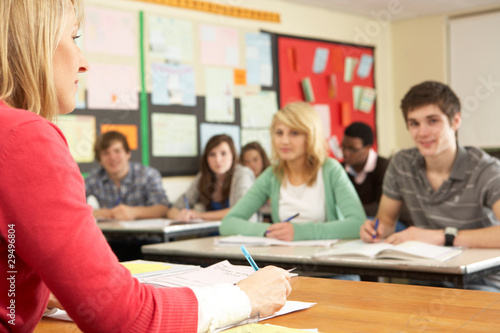 Teenage Students Studying In Classroom With Teacher