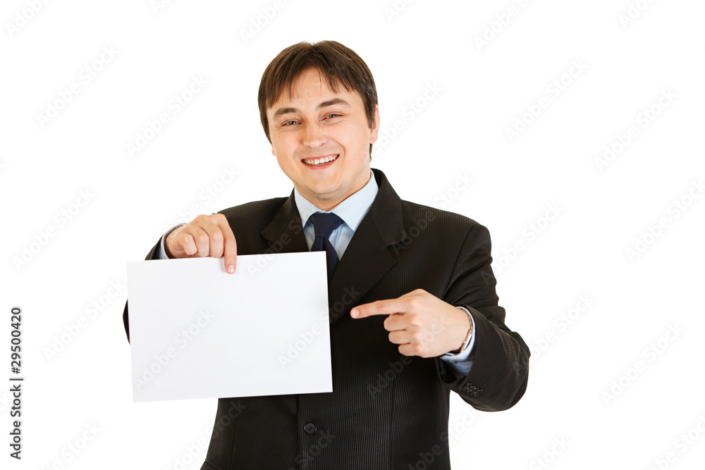 Smiling modern businessman pointing finger at empty white paper Smiling modern businessman pointing finger at empty white paper