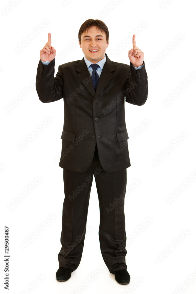 Smiling young businessman pointing up isolated on white. Smiling young businessman pointing up isolated on white.