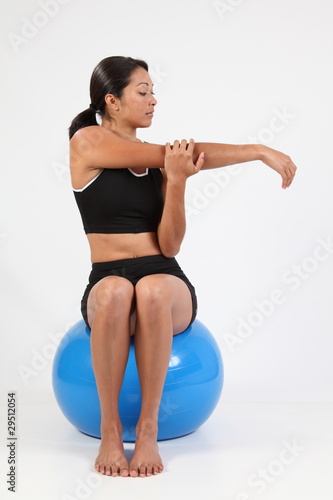 Fit young girl stretching on blue exercise ball