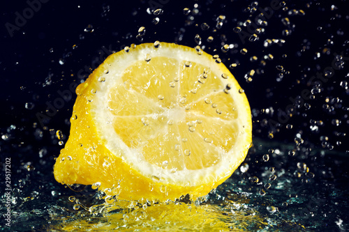 Half of lemon with stopped motion water drops on black