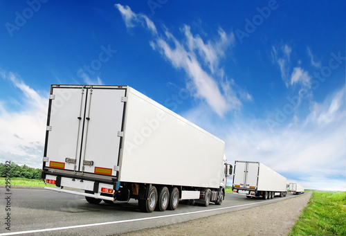 caravan of white trucks on highway under blue sky © Antrey
