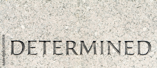 Word "Determined" Carved in Gray Granite Stone