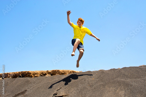 boy has fun jumping in the dunes of the beach into the ocean