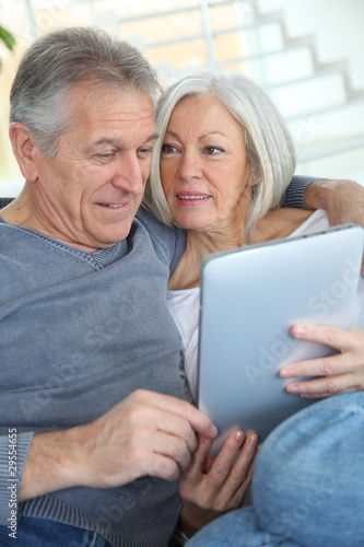 Senior couple sitting in sofa with electronic tablet