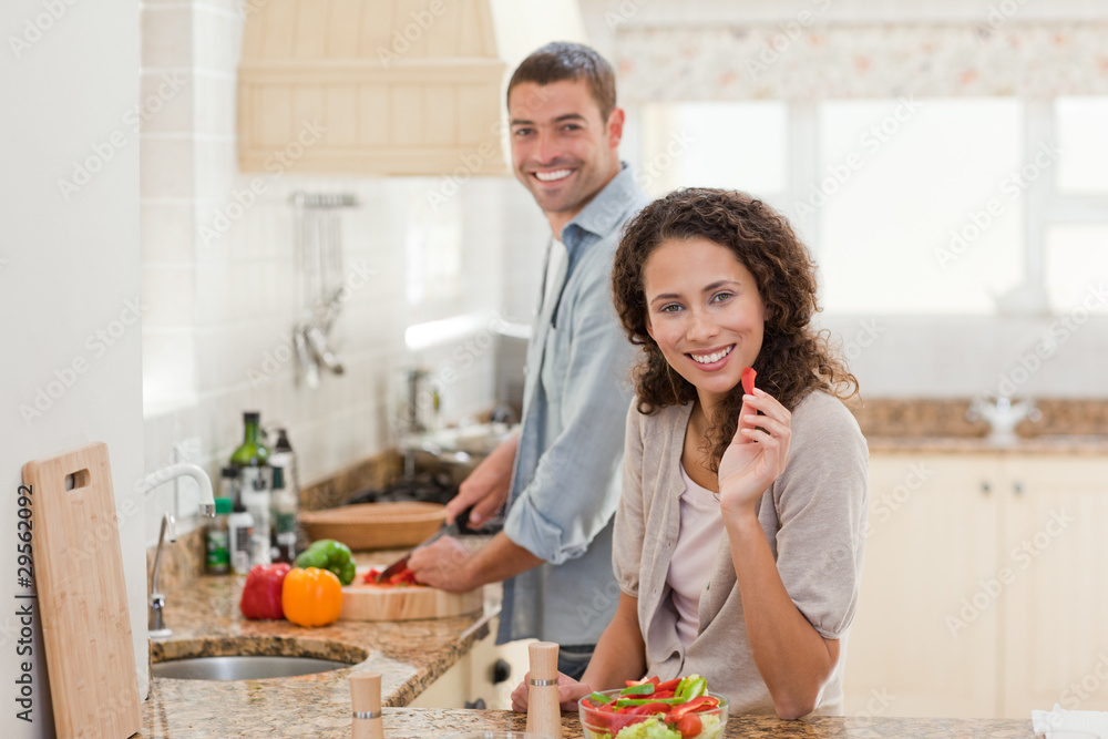 Woman eating while her husband is cooking Woman eating while her husband is cooking
