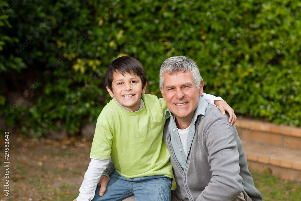 Grandfather with his grandson looking at the camera in the garde Grandfather with his grandson looking at the camera in the garde
