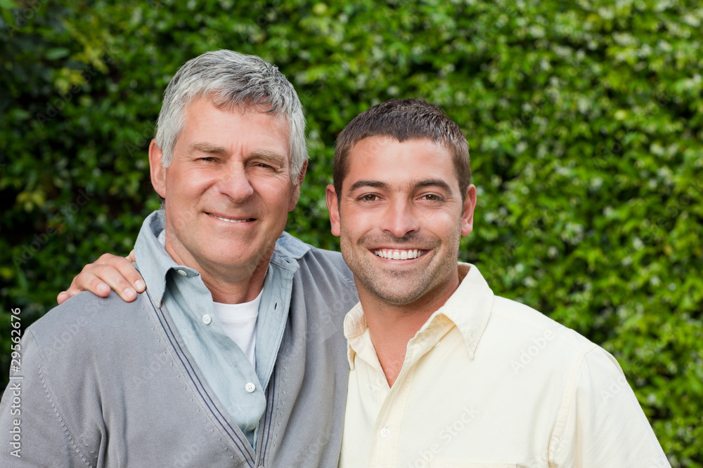 Father and his son looking at the camera in the garden Father and his son looking at the camera in the garden