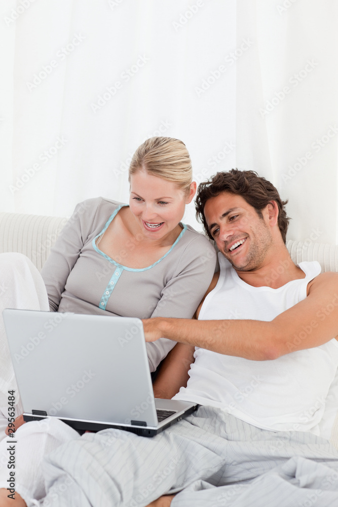 Adorable couple looking at their laptop on the bed Adorable couple looking at their laptop on the bed