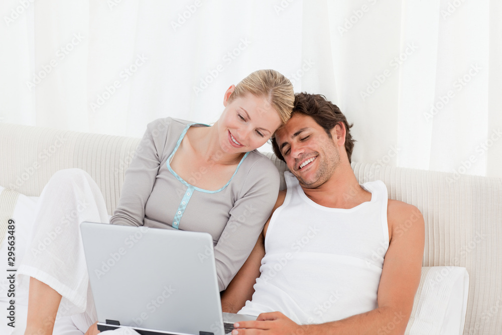 Adorable couple looking at their laptop on the bed Adorable couple looking at their laptop on the bed