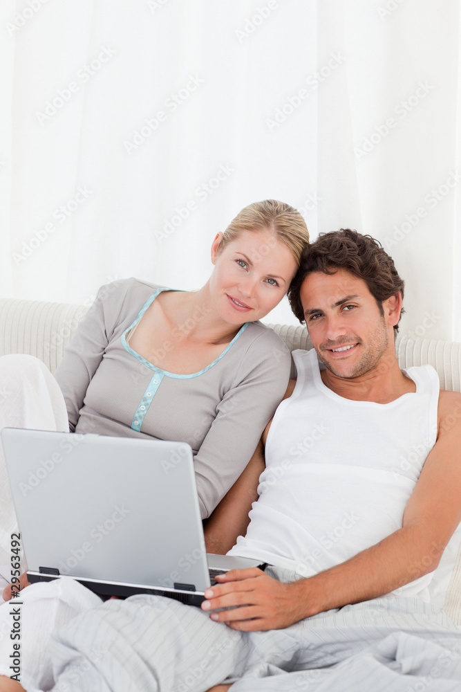 Adorable couple looking at their laptop on the bed Adorable couple looking at their laptop on the bed