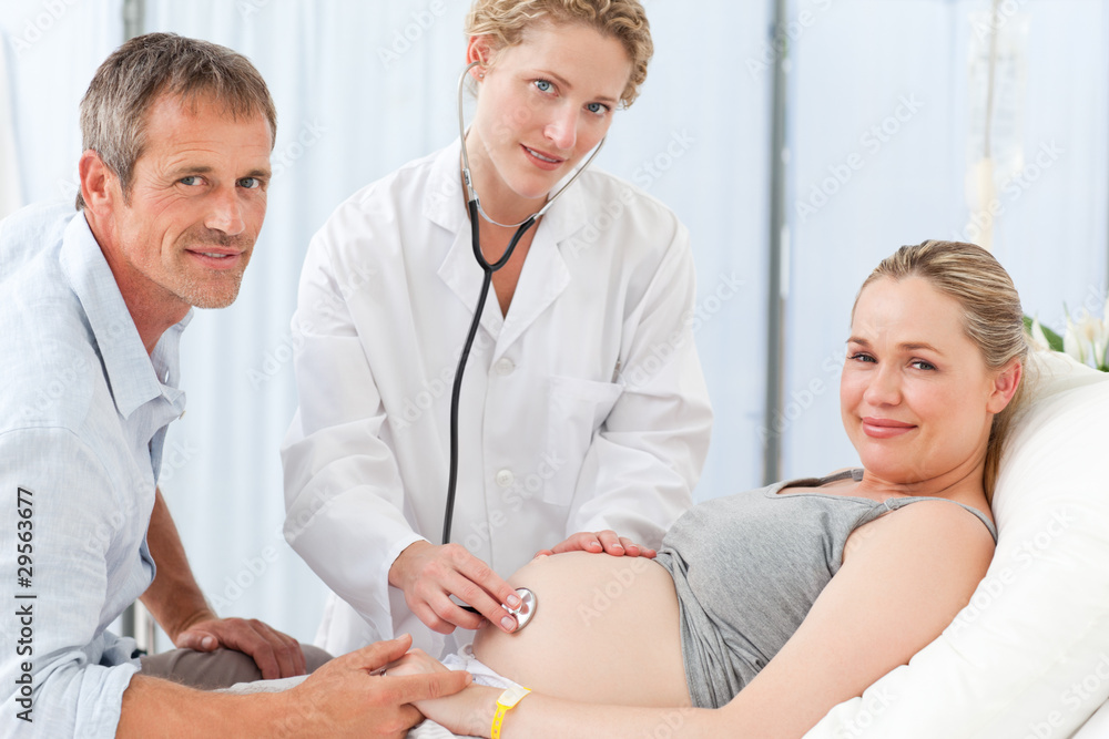 Fototapeta premium Pregnant woman with her husband and the nurse looking at the cam
