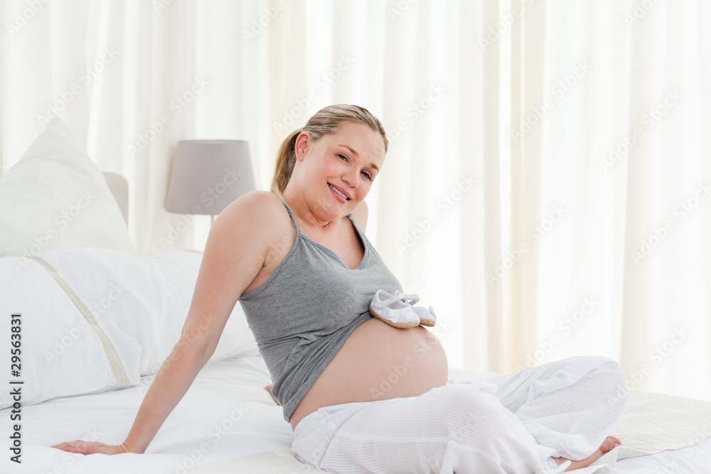 Joyful pregnant woman with childrens shoes on her belly Joyful pregnant woman with childrens shoes on her belly