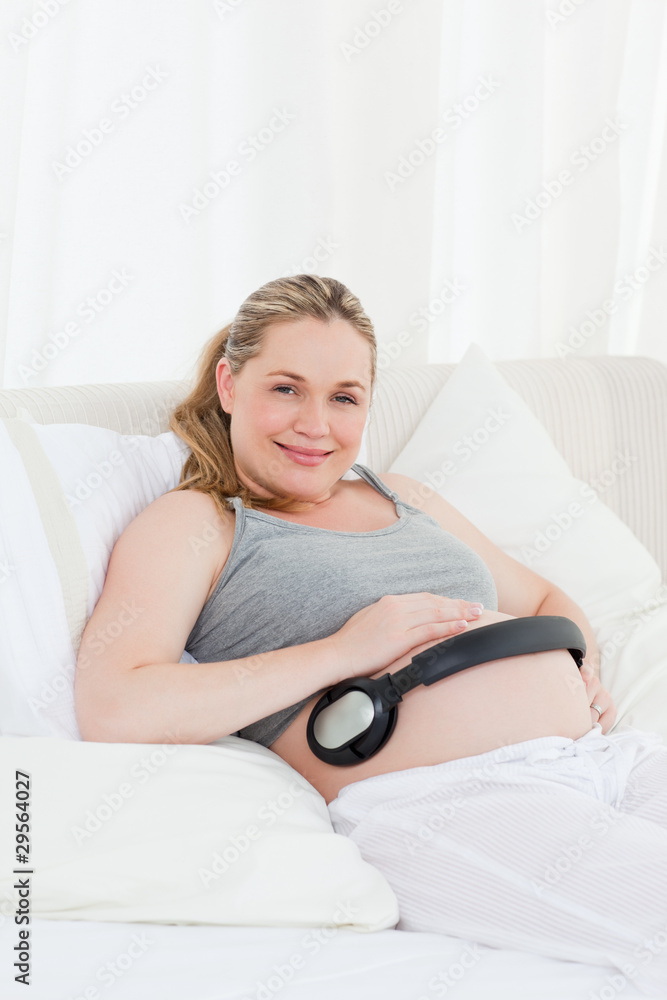 Pregnant woman putting her earphones on her belly Pregnant woman putting her earphones on her belly