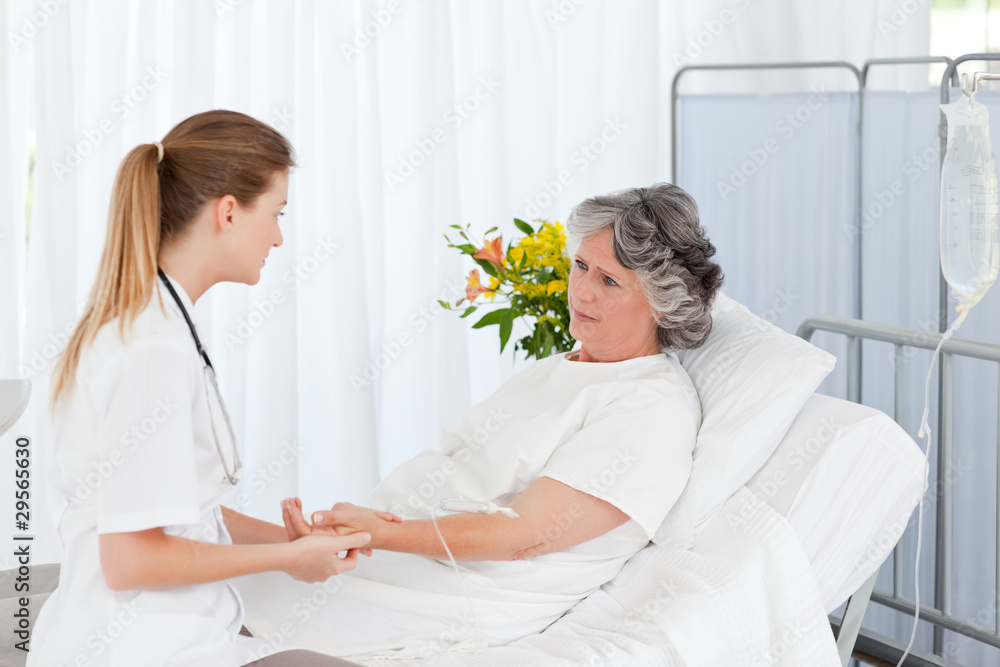 Fototapeta premium Nurse putting a drip on the arm of her patient