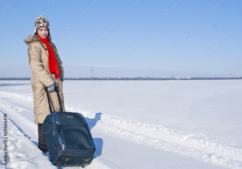 Teen girl with a suitcase outdoors at winter time
