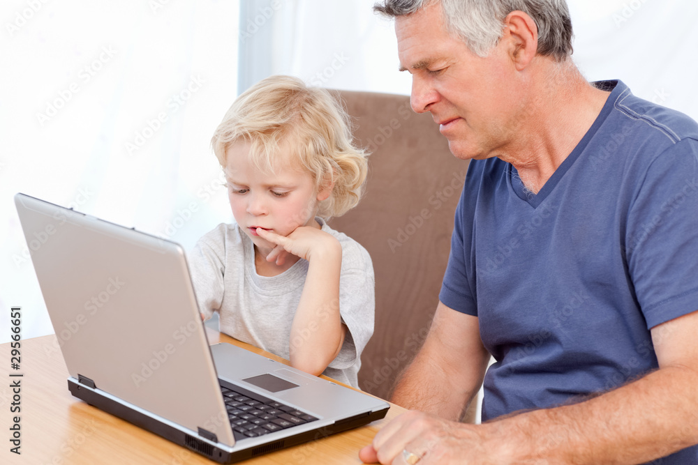 Lovely boy and his grandfather looking at their laptop Lovely boy and his grandfather looking at their laptop