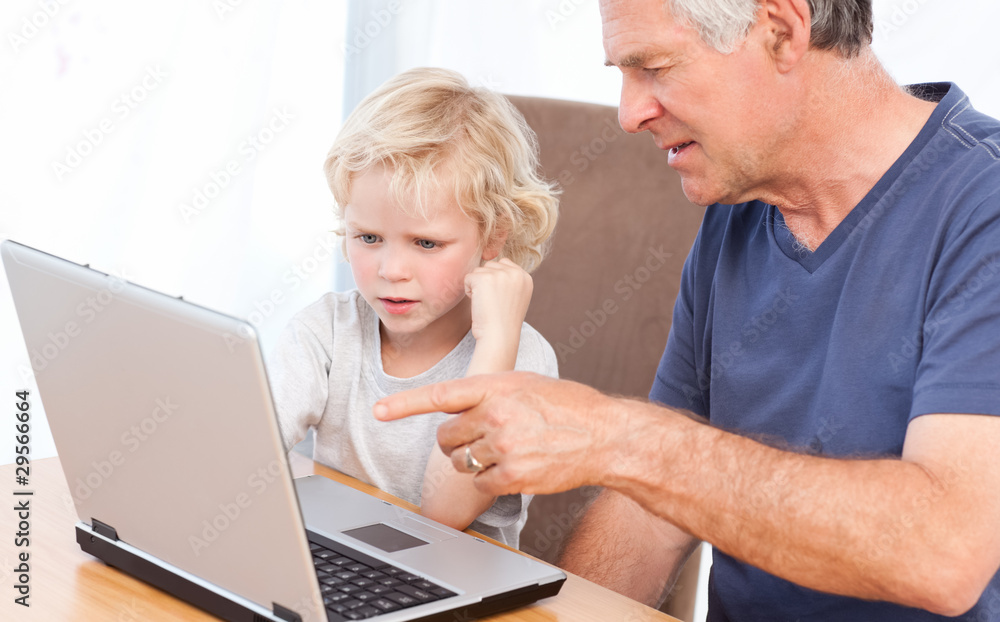 Lovely boy and his grandfather looking at their laptop Lovely boy and his grandfather looking at their laptop