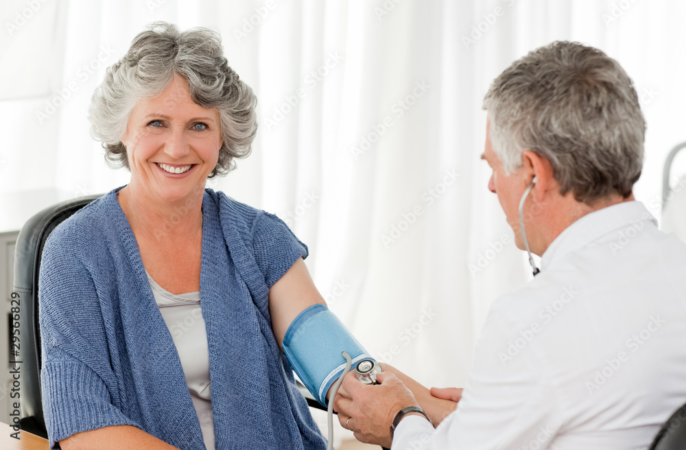A senior doctor taking the blood pressure of his patient A senior doctor taking the blood pressure of his patient