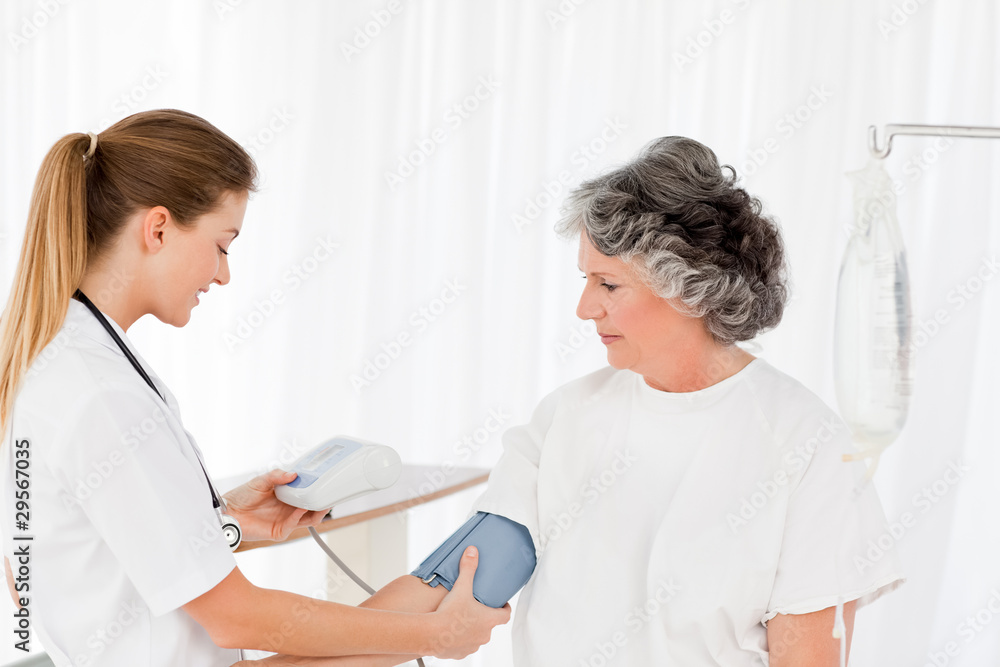 Fototapeta premium Nurse taking the blood pressure of her patient