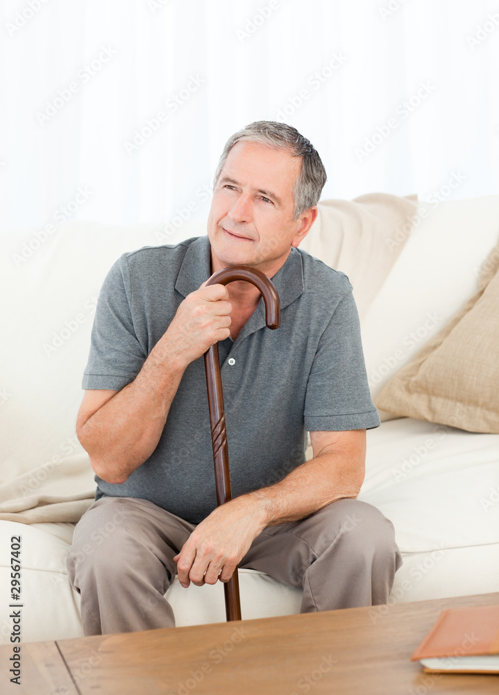 Mature man thoughtful with his walking stick on his bed Mature man thoughtful with his walking stick on his bed