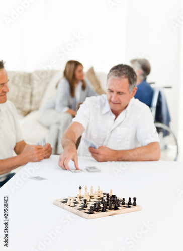 Men playing cards while their wifes are talking