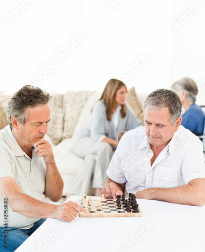 Men playing chess while their wifes are talking