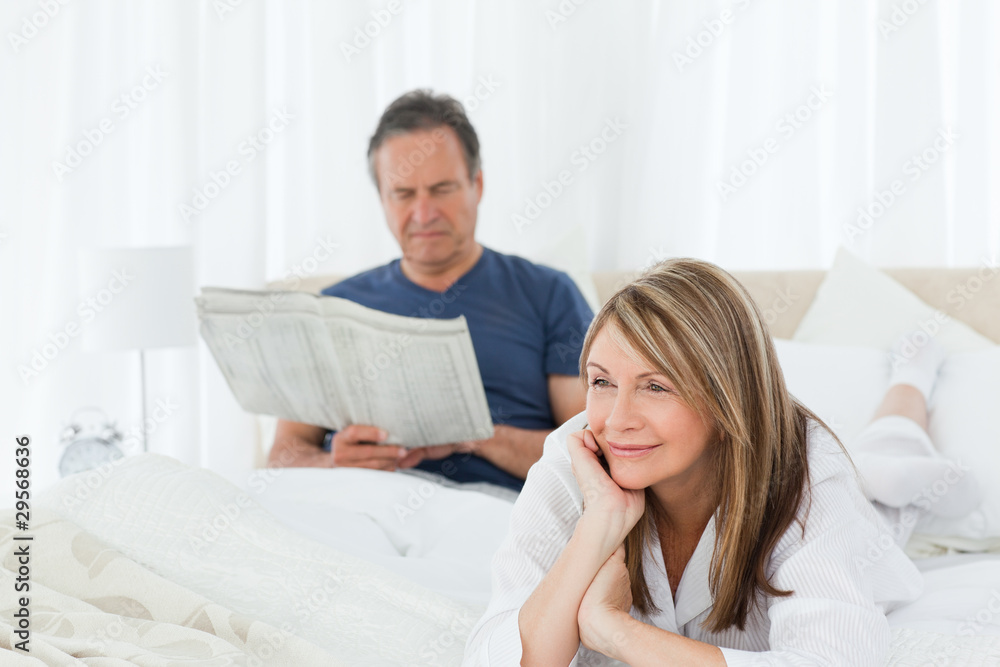 Woman smiling while her husband is reading Woman smiling while her husband is reading